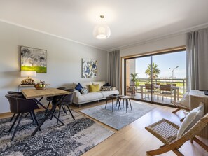 Un salon moderne comprenant un coin repas, un canapé, une table basse et un balcon avec des sièges d’extérieur.