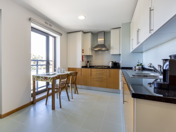 Une cuisine moderne avec des meubles en bois, un plan de travail noir et un coin repas comprenant une table et des chaises.