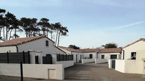 A series of white buildings with tiled roofs, arranged in a courtyard with gravel ground.