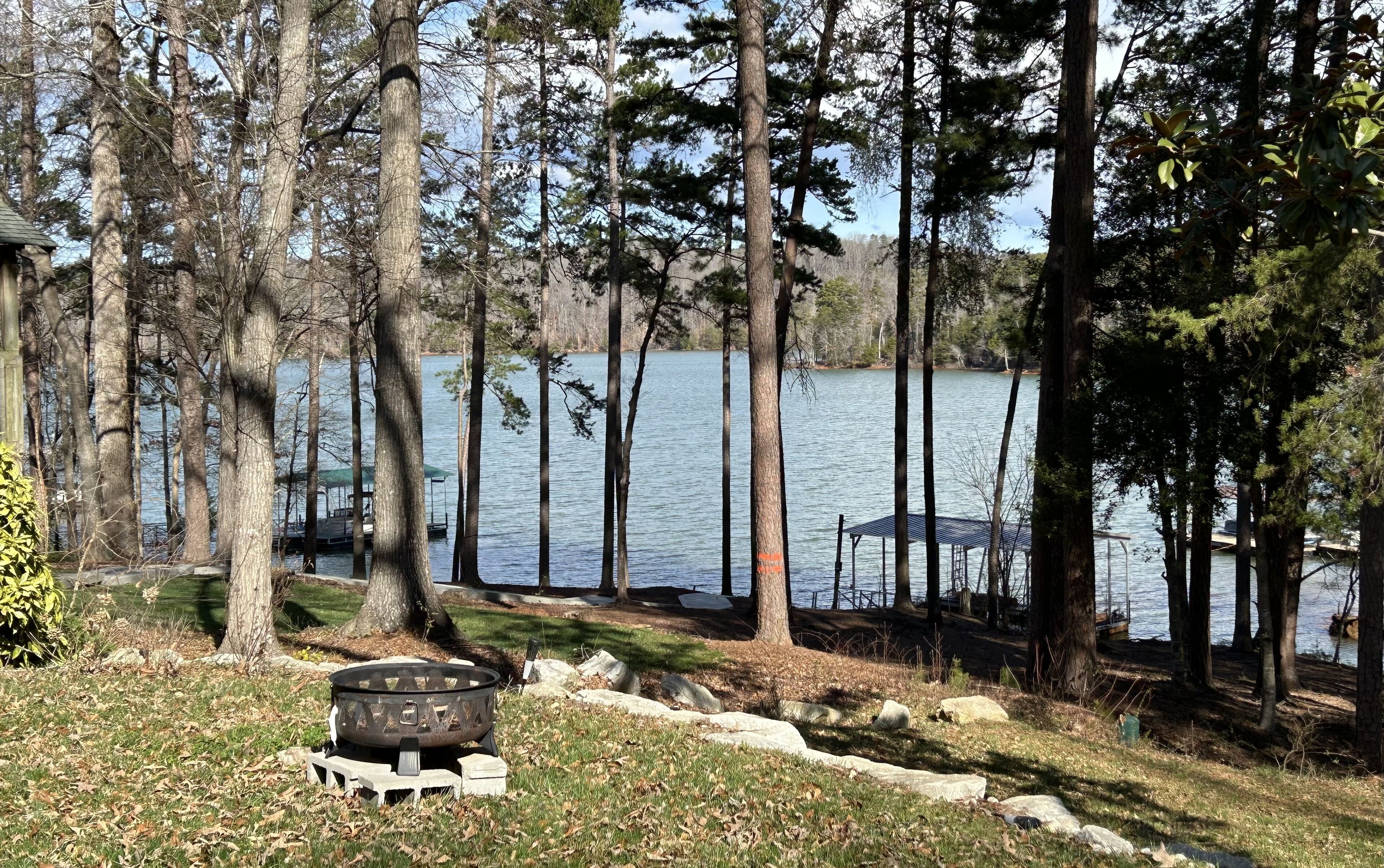 A lakeside property with a fire pit, dock, and docked boat.