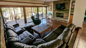 A living room with a leather sofa, a coffee table, and a fireplace. - Cozy 3-bedroom lakefront cottage in beautiful Clemson, SC  (Clemson)