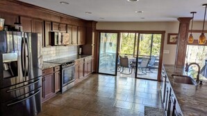 A spacious kitchen with a large island, dark wood cabinets, and a sliding glass door leading to a patio area. - Cozy 3-bedroom lakefront cottage in beautiful Clemson, SC  (Clemson)