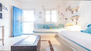 Une pièce avec une porte bleue, un lit recouvert d’une couette blanche et bleue, une table de chevet et une lampe fixée au mur.
