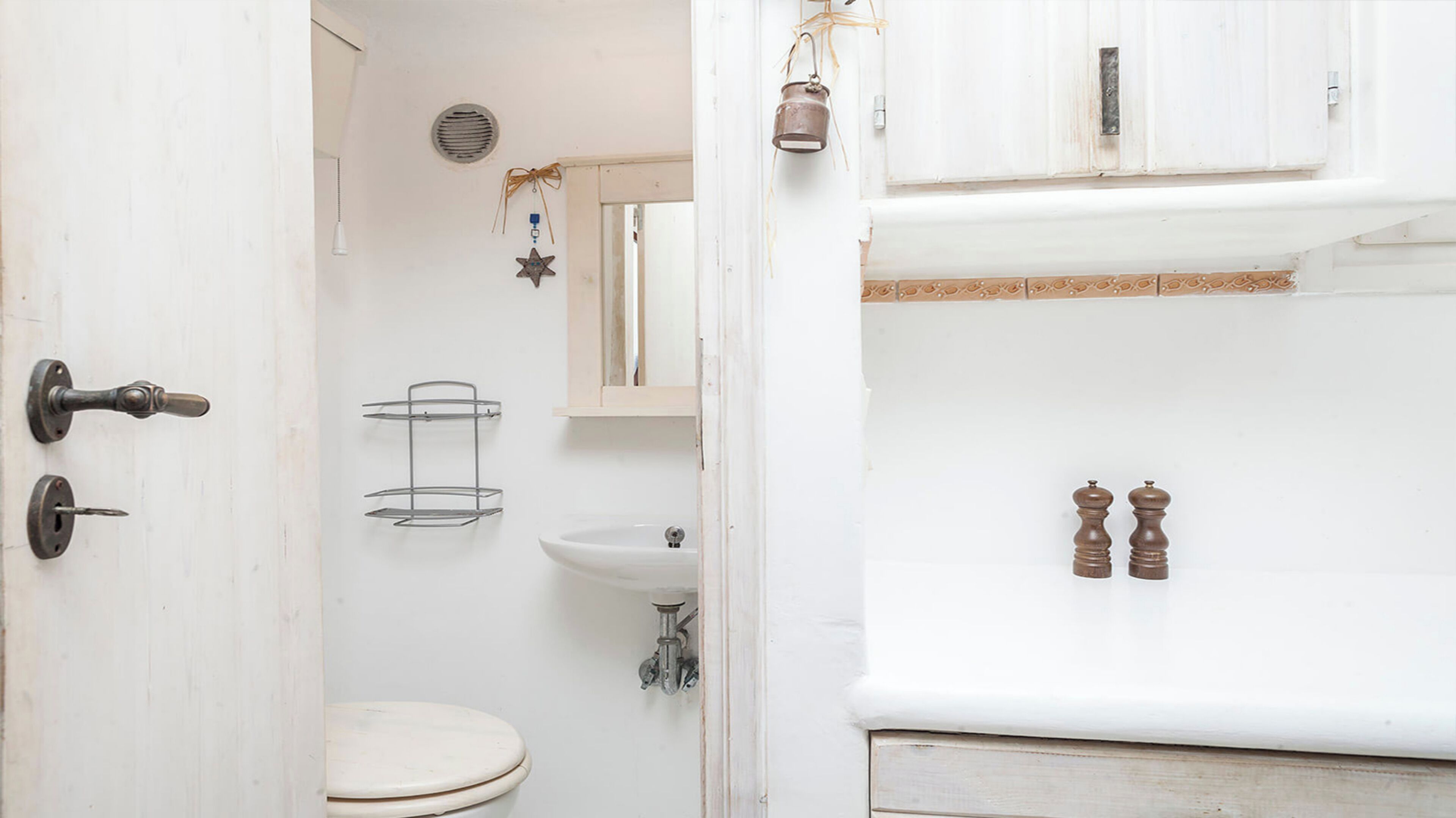 Ein Badezimmer mit Toilette, Waschbecken und einem Metallregal.