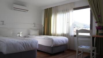 A hotel room with two beds, a desk, and a window with curtains.