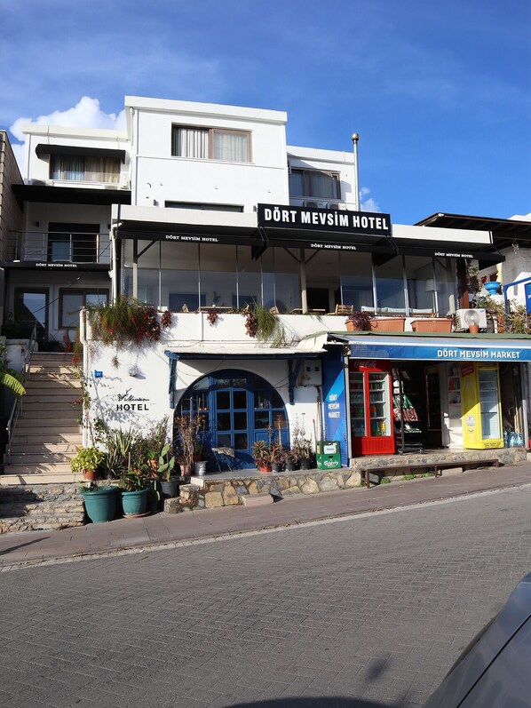 Un hotel con un cartel que dice 'DÖRT MEVŞIM HOTEL' y un mercado con una máquina expendedora de Coca-Cola.