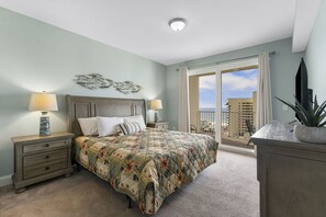 Ein Schlafzimmer mit einem großen Bett, zwei Nachttischen mit Lampen, einer Kommode und Blick auf die Stadt vom Balkon aus.