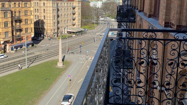 A balcony with wrought iron railings overlooking a city street with buildings and a clear sky. - Luxury Apartment in City Hotspot (Gothenburg)