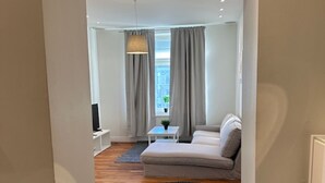 A modern living room with a sofa, a coffee table, and a TV. - Luxury Apartment in City Hotspot (Gothenburg)