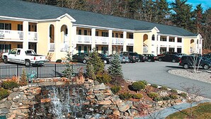 Un motel à plusieurs étages, doté d’un parking et d’une petite cascade décorative en premier plan.