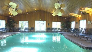 Une piscine dotée de ventilateurs de plafond, de chaises longues et de panneaux de bois.