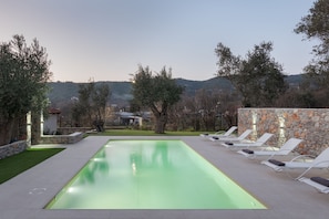 A rectangular swimming pool with a stone wall on one side and lounge chairs on the other. - Nature Retreat Skiathos Villa (Skiathos)