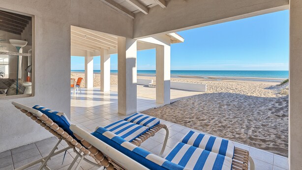 A beachside lounge area with sun loungers and a view of the beach.
