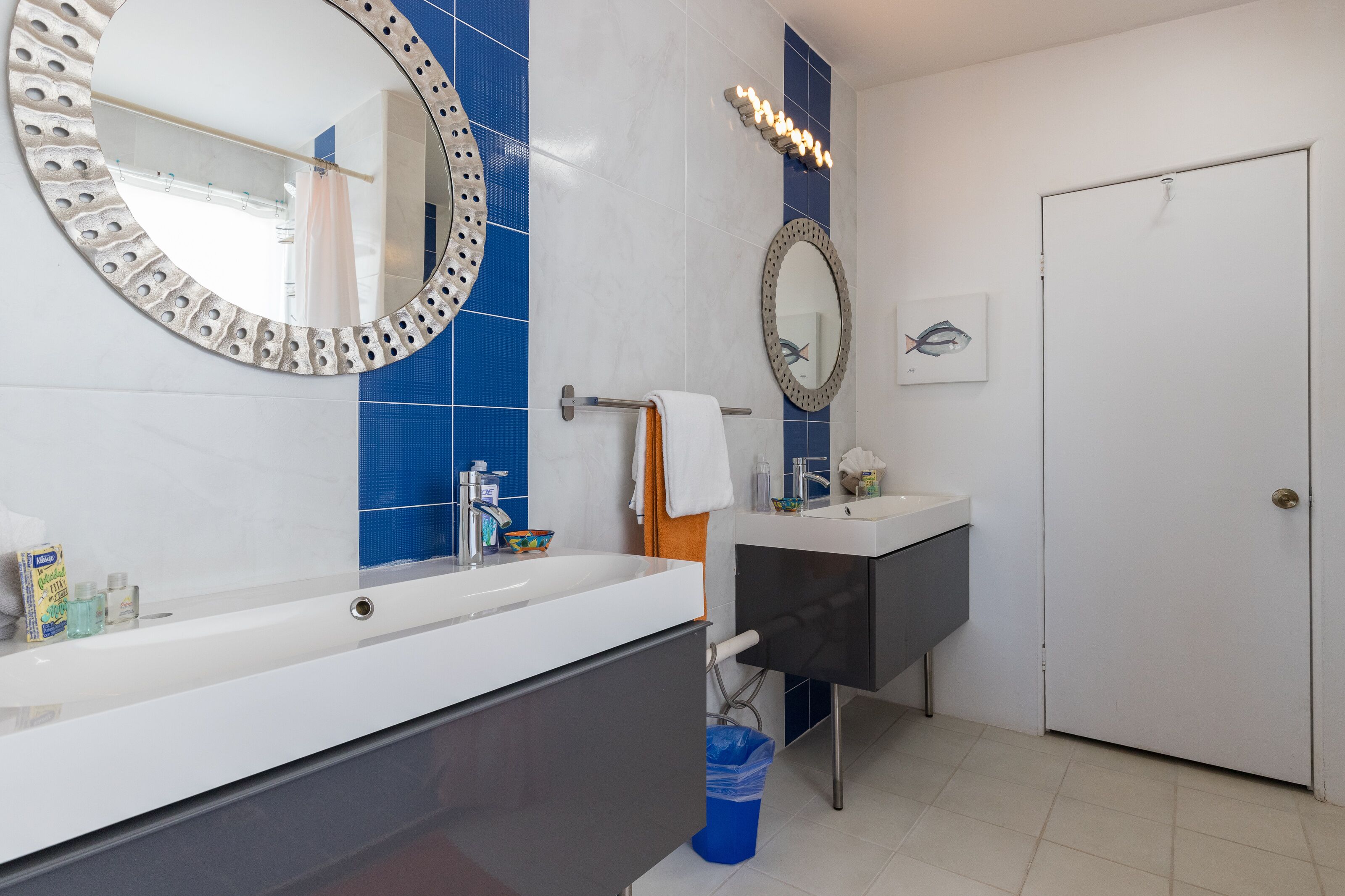Ein Badezimmer mit einem weißen Waschbecken, einem Spiegel und einer blauen Fliesenwand.