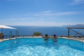 A swimming pool with a view of the sea and mountains.