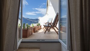 A balcony with a view of mountains, a wooden chair, and potted plants. - Punta di Diamante - 200 Steps to Heaven (Praiano)