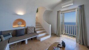 A living room with a staircase, a sofa, a coffee table, and a view of the sea through a balcony. - Punta di Diamante - 200 Steps to Heaven (Praiano)