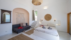 A modern bedroom with a bed, a sofa, a staircase, and decorative wall art. - Punta di Diamante - 200 Steps to Heaven (Praiano)