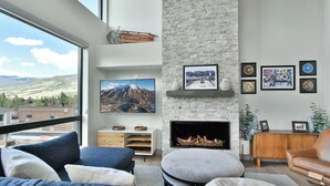 Una sala moderna con chimenea, televisor grande y vistas a la montaña.