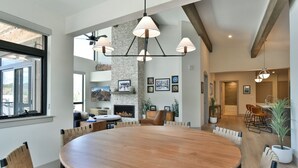 Un comedor amplio con una gran mesa de madera y sillas modernas, una chimenea y una pared de acento de piedra.