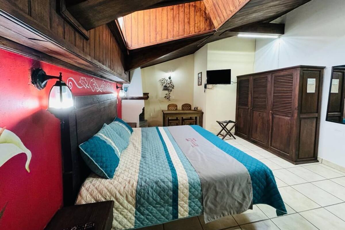 Un dormitorio con cama, techo de madera y pared roja con grafitis.