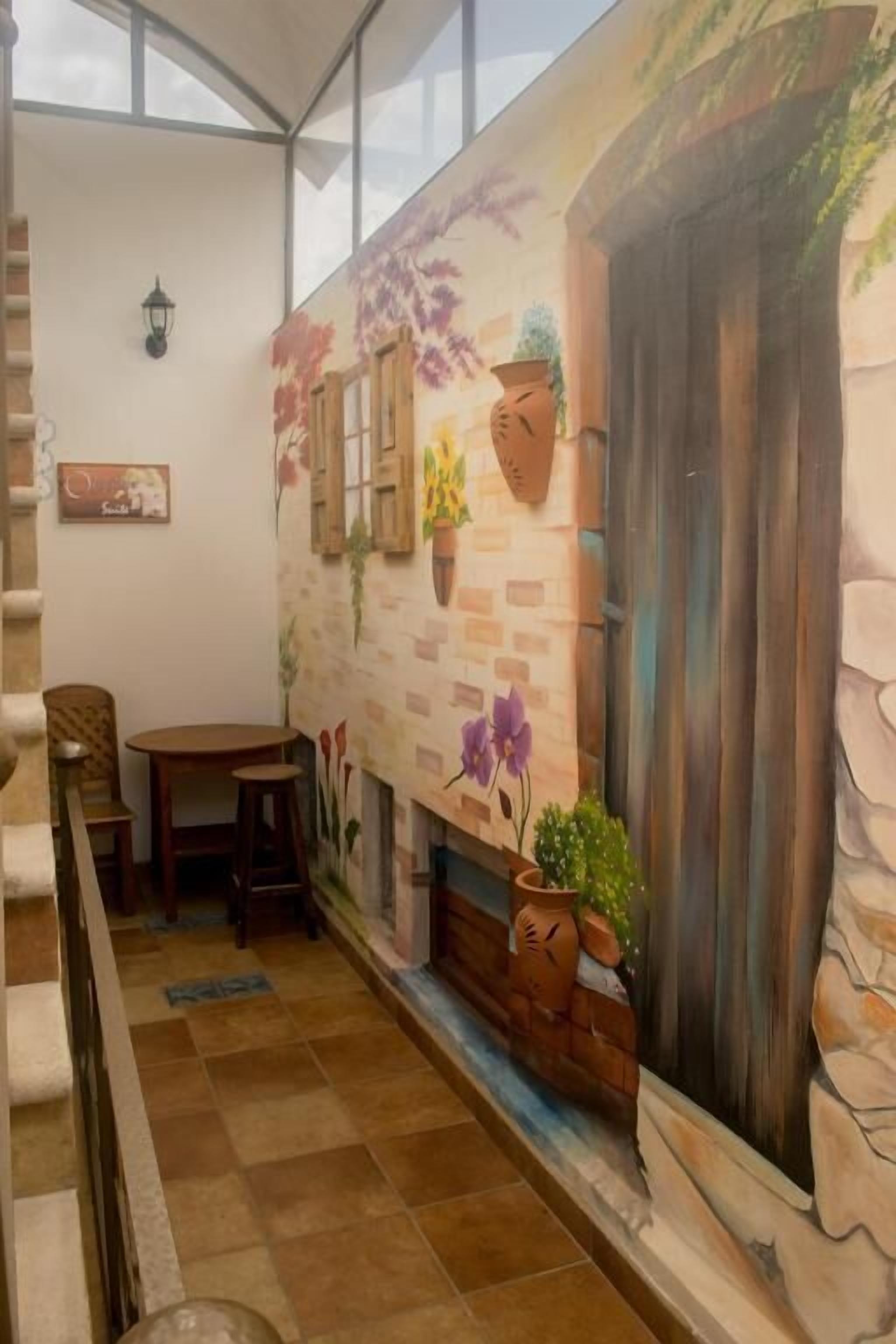 Un espace patio accueillant agrémenté d’une fresque murale, d’une table en bois et de chaises.