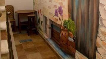 Un espace patio accueillant agrémenté d’une fresque murale, d’une table en bois et de chaises.
