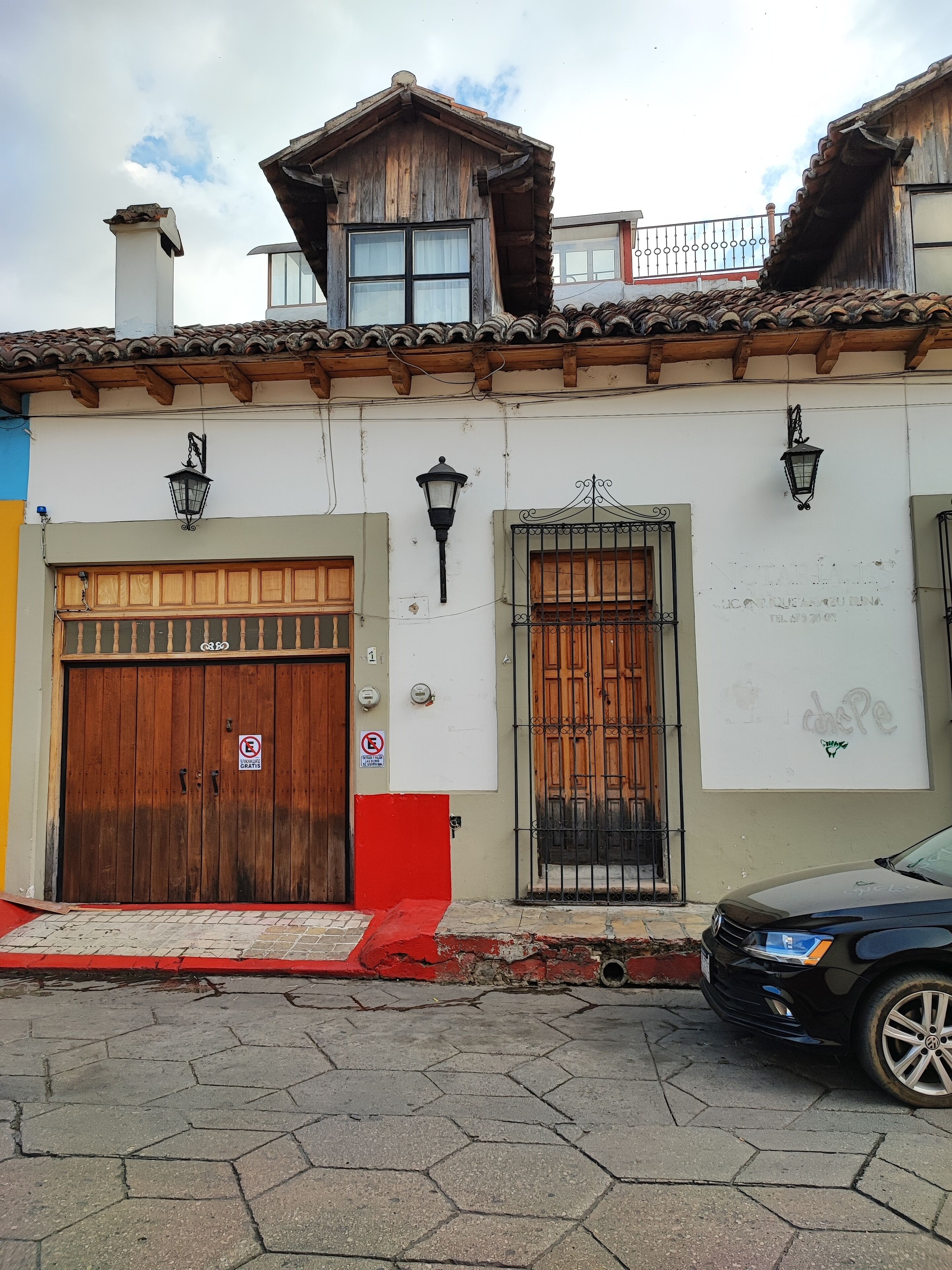 A traditional building with a wooden facade, a large wooden door, and a barred window.