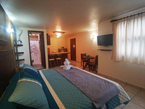 A hotel room with a bed, a desk, a chair, a TV, and a window with curtains.