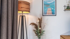 A modern room with a floor lamp, a framed artwork, and a vase with dried plants.