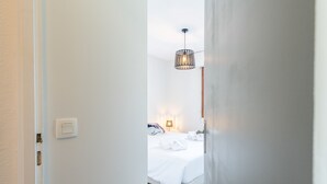 A hotel room with a bed, a bedside lamp, and a hanging light fixture.