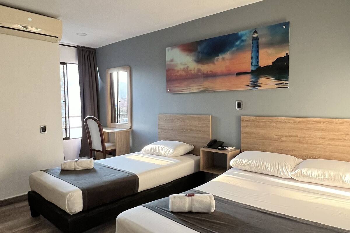Een hotelkamer met twee bedden, een bureau, een stoel en een schilderij van een vuurtoren.