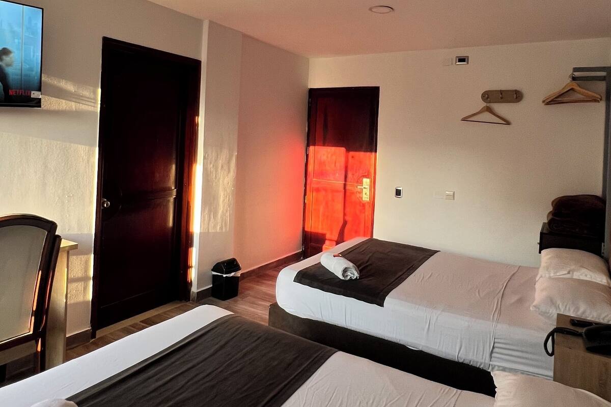 Een hotelkamer met twee bedden, een televisie, een deur en een wandhaak.