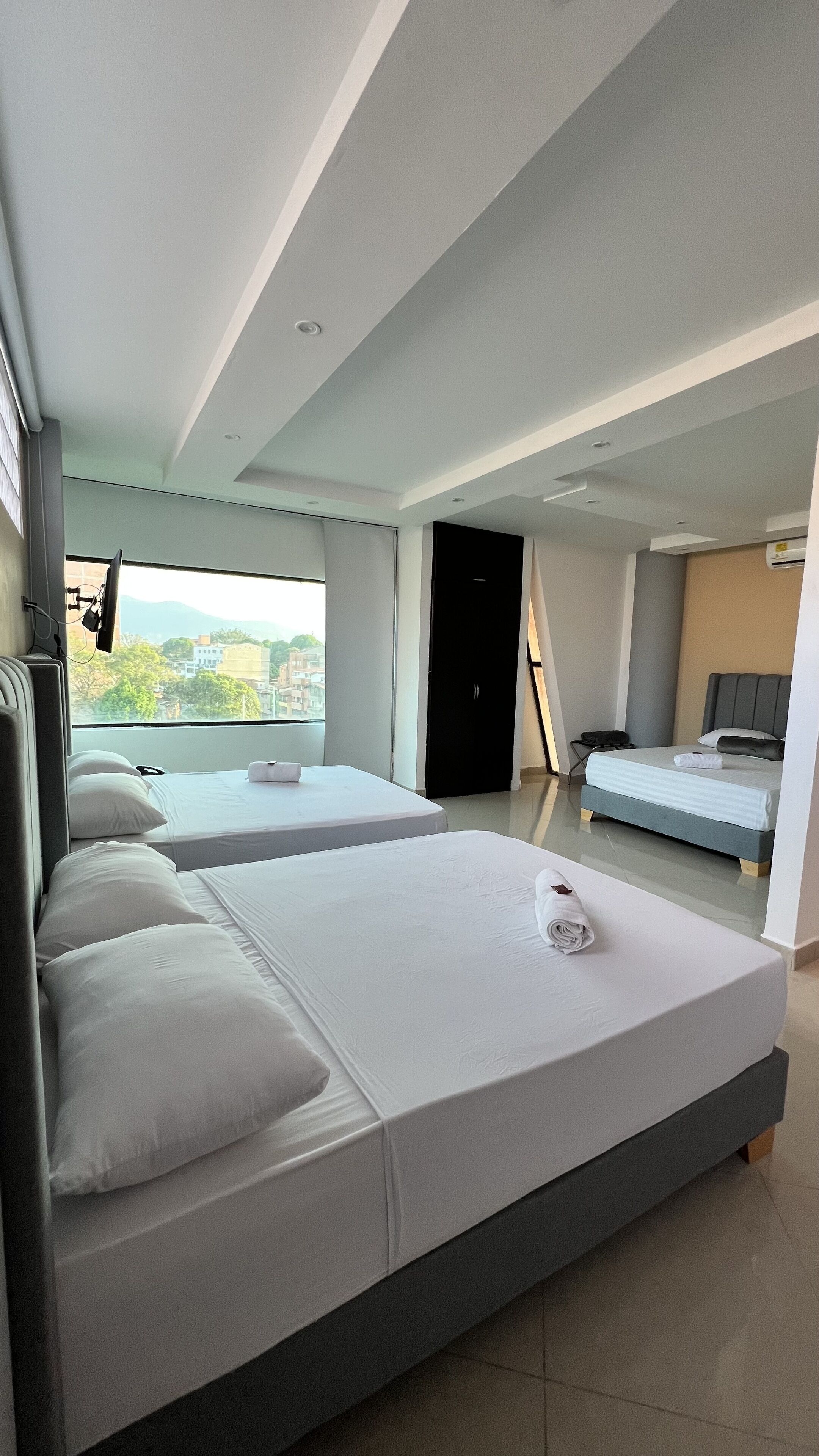 Ein modernes Hotelzimmer mit zwei Betten, einem Fernseher und Blick auf die Stadt.