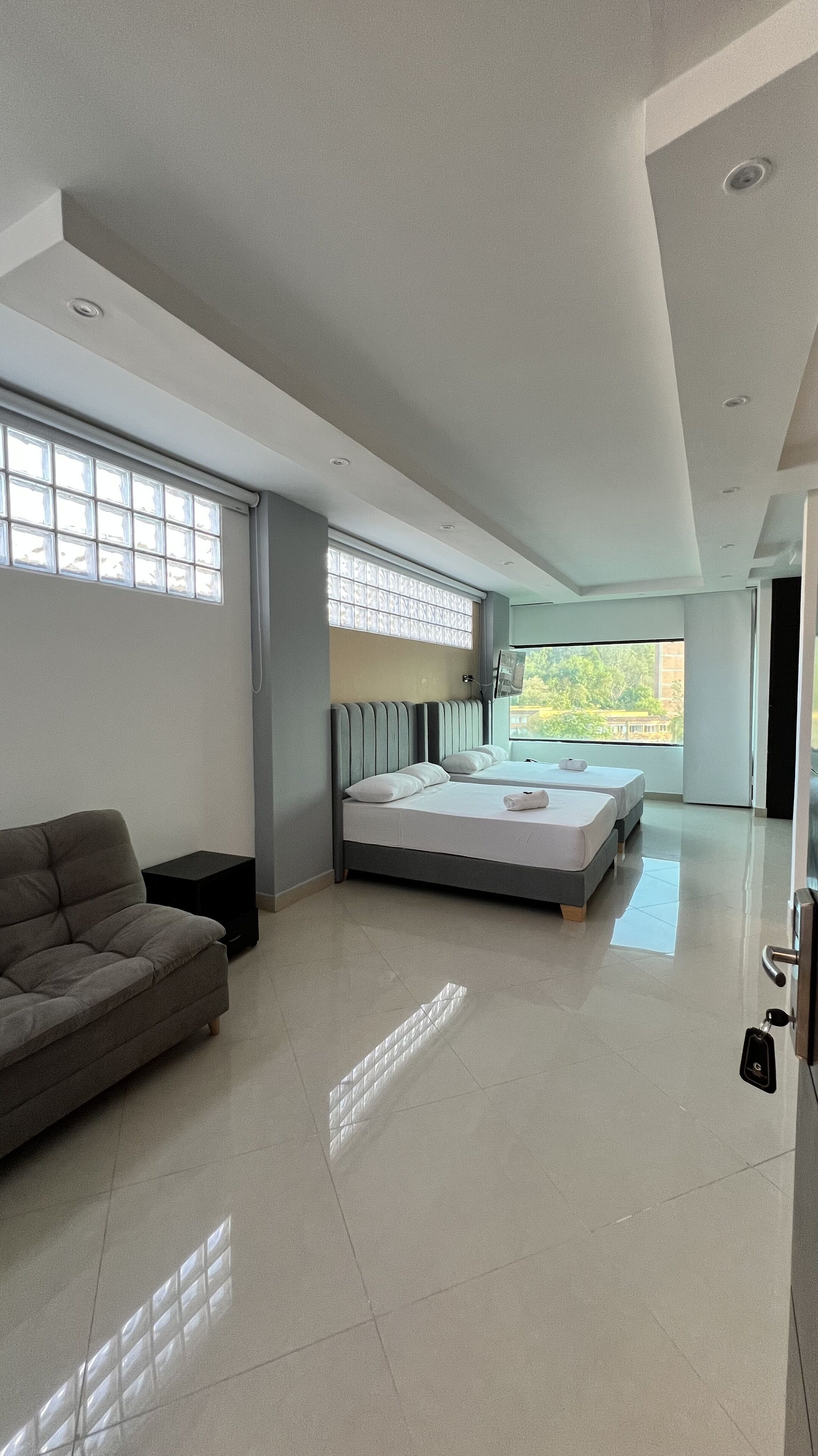 A modern hotel room with a large bed, a sofa, and a TV.