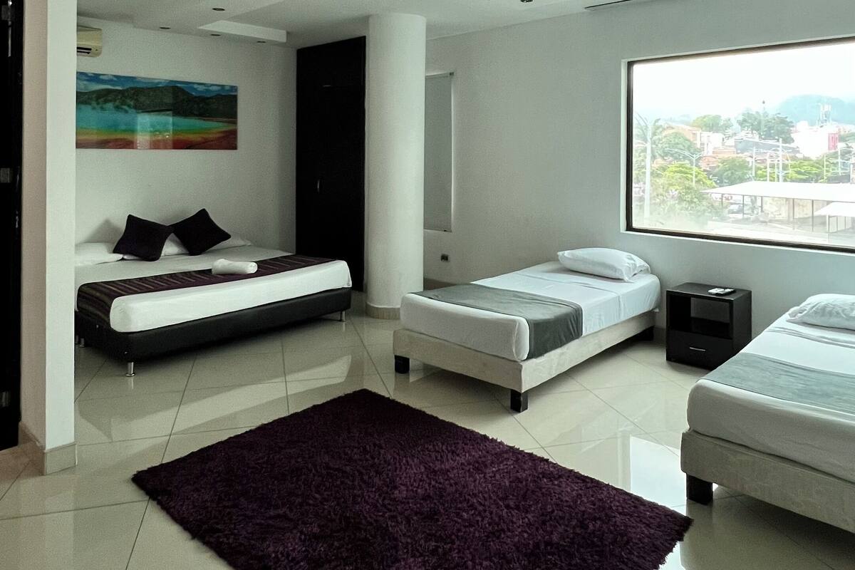Een moderne slaapkamer met twee bedden, een groot raam en uitzicht op de stad.