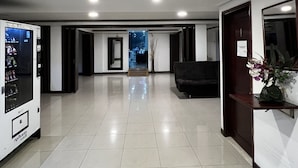 Eine geräumige Lobby mit Verkaufsautomaten, einer Rezeption und einem Durchgang zu einem weiteren Bereich.