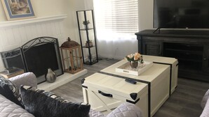 Una sala de estar con chimenea, televisor y una mesa de centro con un jarrón de flores.