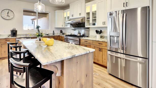 A modern kitchen with white cabinets, a stainless steel refrigerator, a gas stove, and pendant lighting. - Perfect Getaway nestled at the base of Brian Head (Parowan)