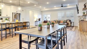 A spacious kitchen with modern appliances, a dining area with a long table and chairs, and a cozy living room with a sofa and a fireplace. - Perfect Getaway nestled at the base of Brian Head (Parowan)