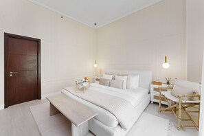 Un dormitorio con una cama grande, mesitas de noche, un banco y un escritorio con una silla.