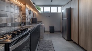 A modern kitchen with a gas stove, stainless steel appliances, and a large window providing natural light. - Complete 2 bedroom apartment (São Paulo)
