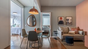 A modern living room with a sofa, chairs, a coffee table, and a dining area with a table and chairs. There is a mirror on the wall and artwork above the sofa. - Complete 2 bedroom apartment (São Paulo)