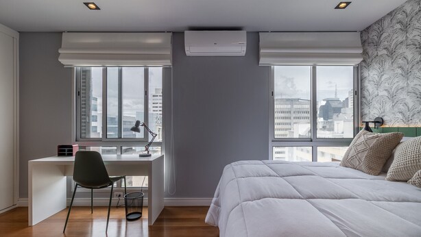 A modern bedroom with a large bed, a desk, and a chair, featuring large windows and a city view. - Complete 2 bedroom apartment (São Paulo)