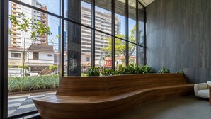 A modern interior with a curved wooden bench, large windows, and a view of urban buildings.