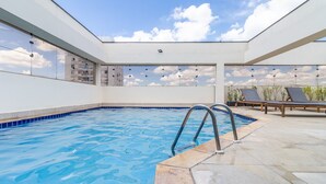 An indoor swimming pool with clear blue water, a tiled floor, and a view of the sky through a skylight. - Haddock_166' 1 bedroom apartment in Jardins (São Paulo)