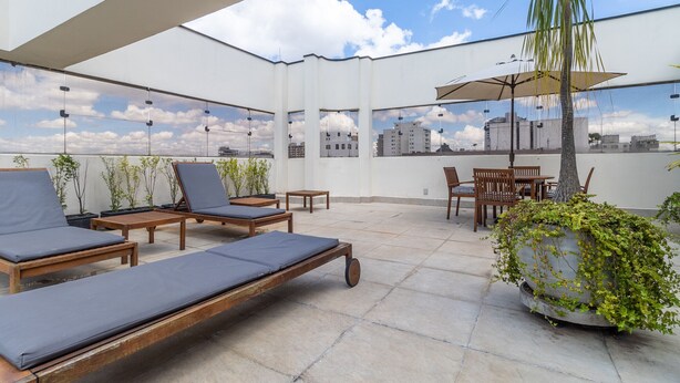 A rooftop terrace with lounge chairs, a table, and a potted plant. - Haddock_166' 1 bedroom apartment in Jardins (São Paulo)