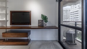 A modern living room with a flat-screen TV, a framed picture, and a decorative plant. - Haddock_166' 1 bedroom apartment in Jardins (São Paulo)