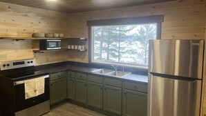 Eine Küche mit Holzwänden, einem Edelstahlkühlschrank, einer Mikrowelle und einem Spülbecken.