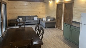 Ein gemütliches Blockhaus-Interieur mit Holzausstattung, einer Essecke und einer Küchenzeile.